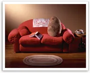 Red couch with a potato, open book, table with mug, and a small rug, suggesting coziness and relaxation.