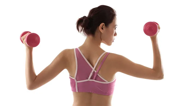 Rear view of a woman in a pink sports bra lifting pink dumbbells, showcasing athletic strength and posture.