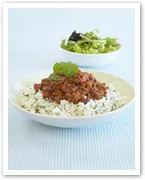 Plate of rice topped with meat sauce, garnished with cilantro, and a side of fresh green salad in a bowl.