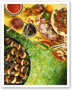 A colorful assortment of grilled skewers, sauces, and spices on a grassy picnic setting.
