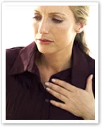 A woman in a maroon shirt holding her chest, possibly experiencing discomfort or symptoms related to heart disease.