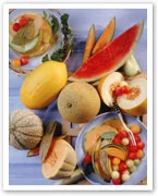 Mixed melons including watermelon, cantaloupe, honeydew, and sliced fruit salad on a wooden board.