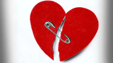 A broken red heart with halves joined by a safety pin, symbolizing an attempt to mend or heal.