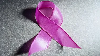 Pink ribbon symbolizing breast cancer awareness on a textured gray background.