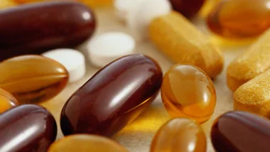 Various vitamin capsules and tablets in close-up view on a surface.