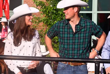 Kate and William wearing cowboy hats, smiling at each other outdoors in Canada.