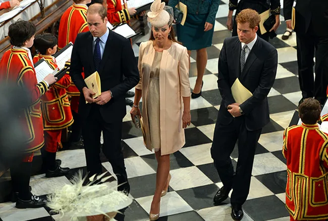 Group of elegantly dressed people in formal attire walking in a checkered floor venue.
