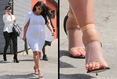 Pregnant woman in white dress walks in clear heels; focus on swollen feet.