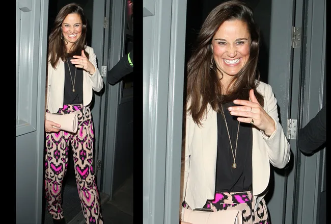 Pippa Middleton smiling and leaving a venue, wearing a black top, patterned pants, and holding a clutch.