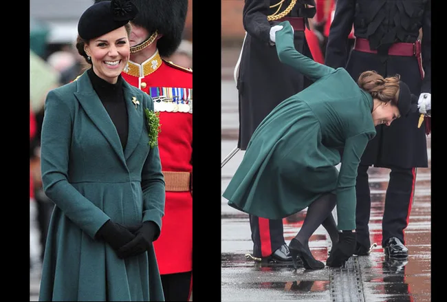 A woman in a green coat with a hat smiles and bends down in a public event, showing her dress partially lifted by the wind.
