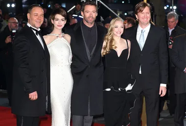 Four people in formal wear on the red carpet at the "Les Misérables" premiere, smiling for the cameras.