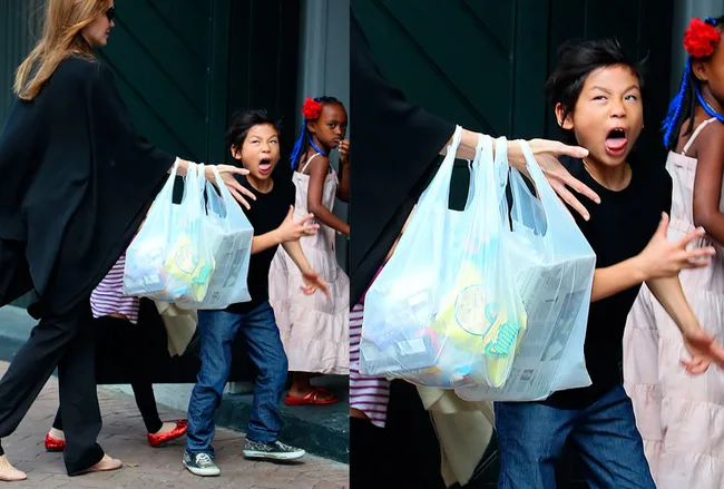 A child expresses excitement while walking outside, accompanied by adults holding shopping bags.