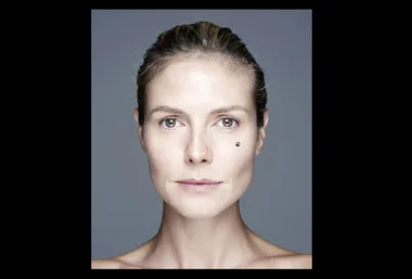 A woman with no makeup, hair pulled back, neutral expression, light background.