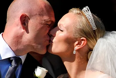 A bride and groom sharing a kiss on their wedding day, the bride wears a tiara and veil, both in formal attire.
