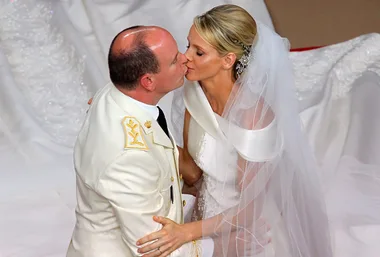 Couple in a white wedding attire sharing a kiss in an elegant ceremony setting.