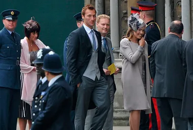 Guests arriving at a royal wedding, some in formal attire, police officers and military personnel present.