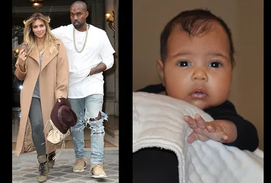 Couple walking: woman in camel coat holding hat; man in ripped jeans. Infant reaching forward, wrapped in a blanket.