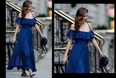 Woman in a blue off-shoulder dress walking down stairs, holding a black fringed bag.