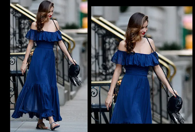 Woman in a blue off-shoulder dress walking down stairs, holding a black fringed bag.