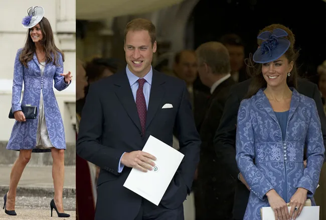 Two individuals at an event, one wearing a blue patterned coat and hat, the other in a dark suit holding papers.