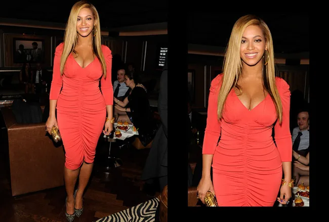 A woman in a form-fitting, bright orange dress at an indoor event, holding a gold clutch, and smiling at the camera.