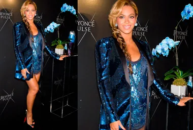 Beyoncé in a sparkling blue outfit with a braided hairstyle at a Beyoncé Pulse event, standing beside blue orchids.