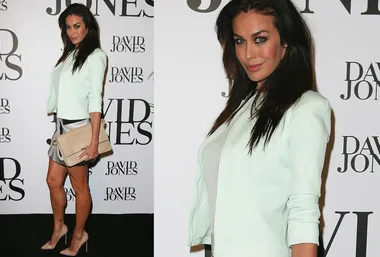 A woman in a light suit attends the David Jones event, posing on a red carpet with logos in the background.