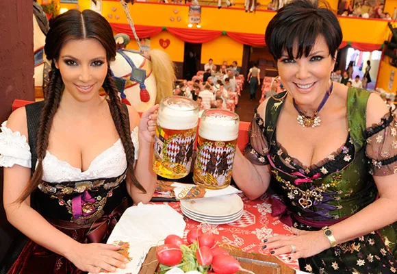 Mother and daughter in traditional outfits holding beer mugs at a festive event.
