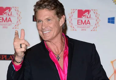 Man in a suit with a pink shirt poses playfully on the red carpet at MTV EMA 2012 in Frankfurt.