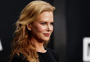 A woman with long, wavy blonde hair wearing a black outfit at a formal event, facing slightly to the left.