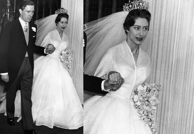 A bride in a wedding dress and tiara holds a bouquet, walking hand in hand with a groom in formal attire.