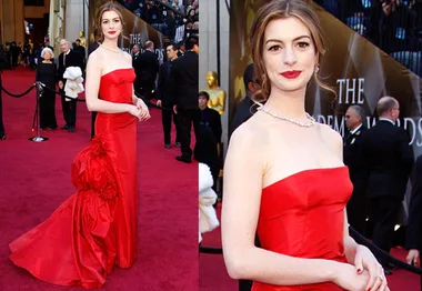 Actress in red strapless gown with floral detail on the 2011 Oscars red carpet.