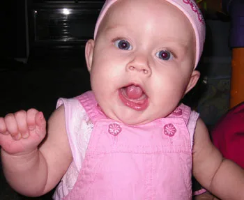 Baby wearing pink outfit with a surprised expression.