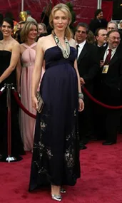 A person in a dark gown poses on the red carpet at the 80th Academy Awards, surrounded by other attendees.
