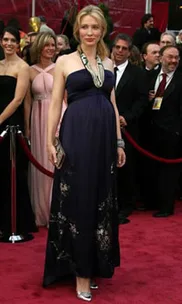 A person in a dark gown poses on the red carpet at the 80th Academy Awards, surrounded by other attendees.