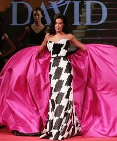 Model in black-and-white gown on runway, holding pink fabric with "DAVID" in background.
