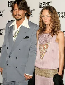 A man in a gray suit and a woman in a lavender dress holding hands at a Montblanc event.