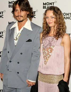 A man in a gray suit and a woman in a lavender dress holding hands at a Montblanc event.