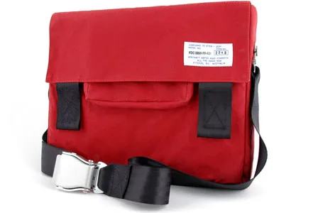 Red messenger bag with black strap and silver buckle, featuring a white label on the top right.