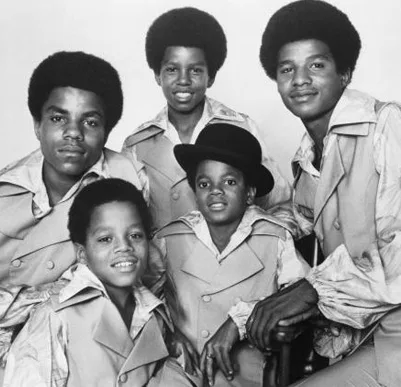 Group photo of The Jackson 5, young Michael Jackson at the center, all wearing matching outfits and smiling.
