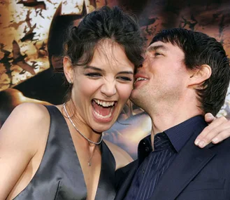 Man whispering to laughing woman at Batman-themed event.