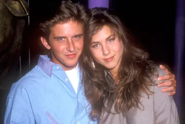 Young woman and man posing together, smiling with arms around each other in a casual setting.