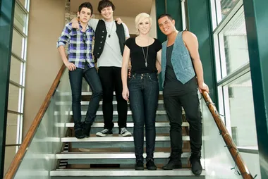 Four individuals standing on a staircase, casually dressed, posing for a group photo.