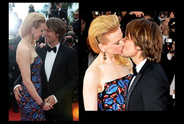 Man and woman in formal attire share a kiss on the red carpet, surrounded by photographers.