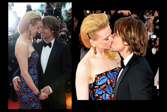 Man and woman in formal attire share a kiss on the red carpet, surrounded by photographers.