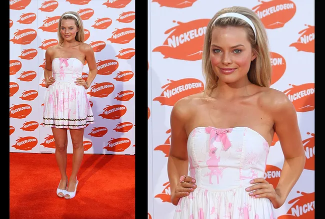 Blonde woman in a strapless white and pink dress poses on the red carpet at a Nickelodeon event.