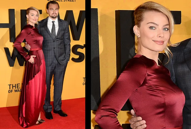 Actors in formal attire at a movie premiere; woman in red dress, man in gray suit against a yellow backdrop.