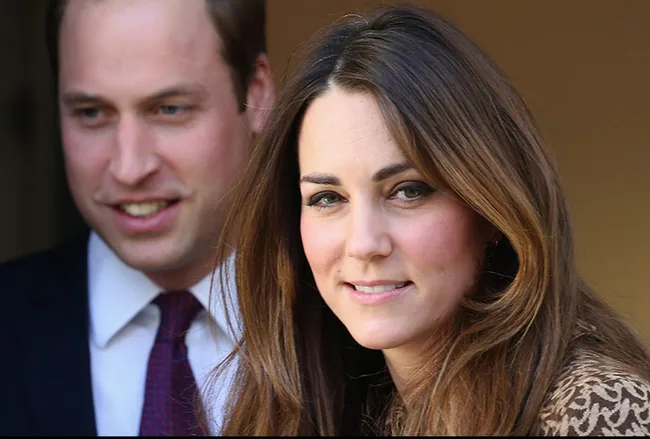 Two individuals smiling, one in the foreground with long hair, and another slightly blurred in the background wearing a suit.