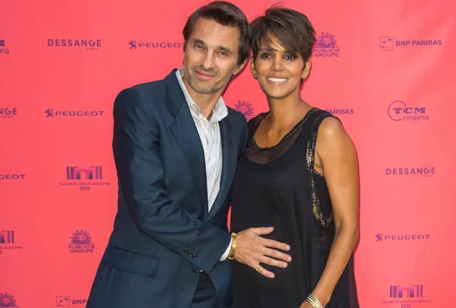 A man and a woman smiling, standing together on a red carpet at a film festival event.