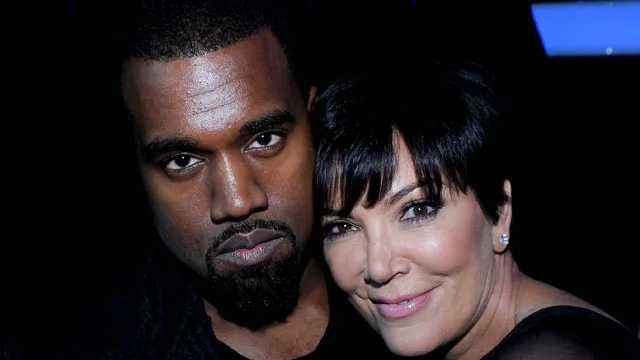 Kanye West and Kris Jenner smiling and posing closely together in a dimly lit setting.